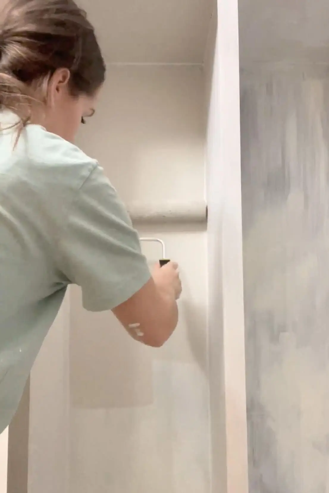 Using a paint roller to apply white paint inside the storage cubbies, ensuring even coverage for a clean, finished look.